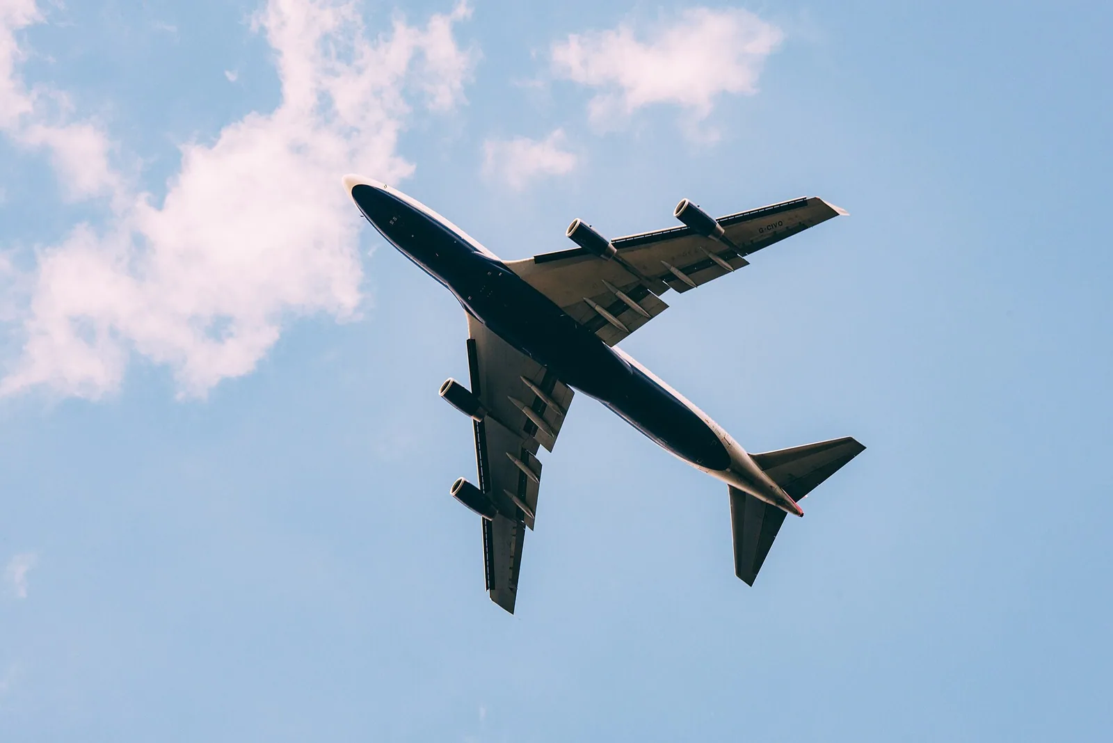 Passenger aircraft flying overhead against a bright blue sky