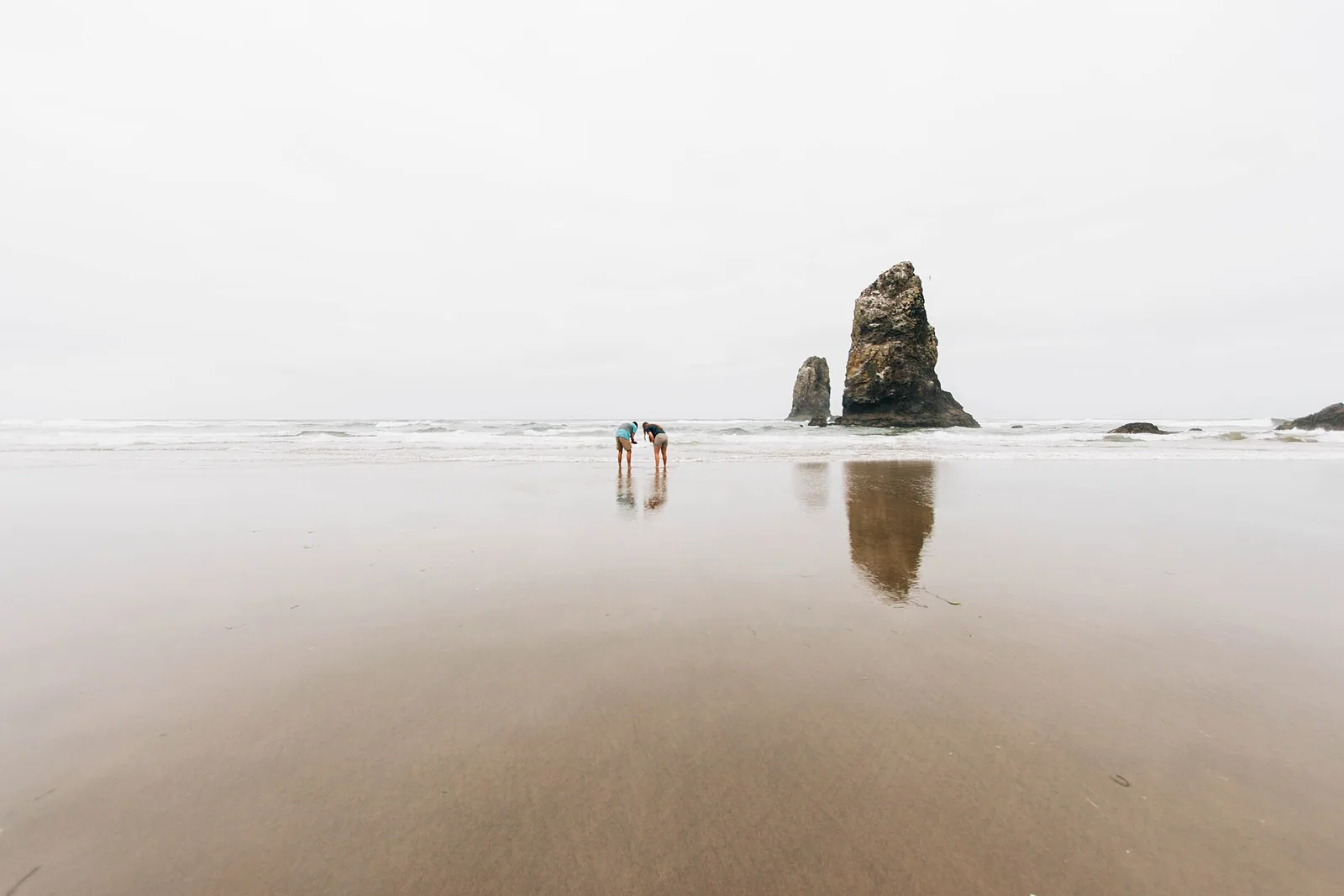 Two travelers standing together on a wide beach